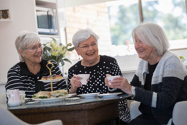 three over55s independent living ladies enjoying tea in the community centre of the retirement village for downsizing